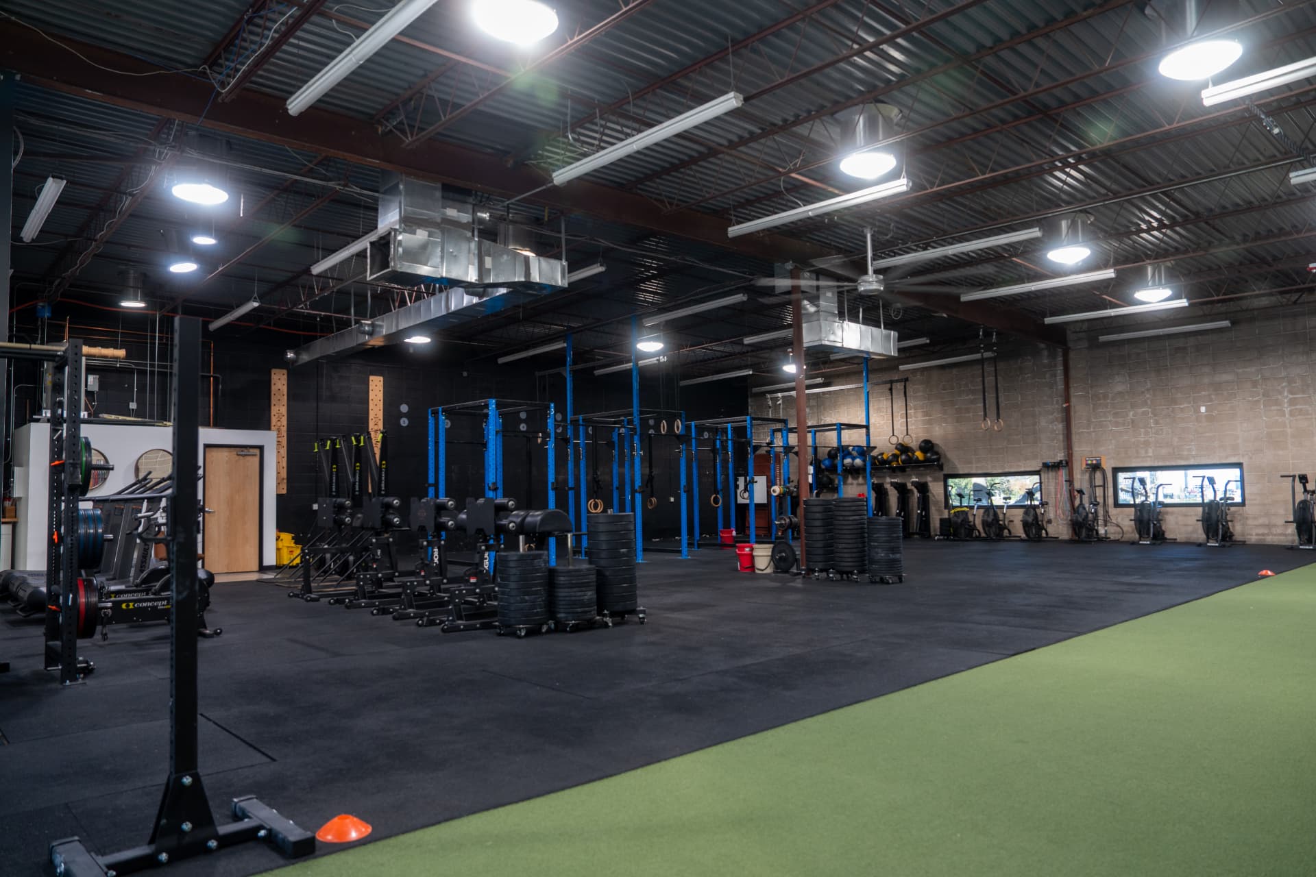 Training floor at Arsenal Health DTC with squat racks, sleds, rowers and a turf lane