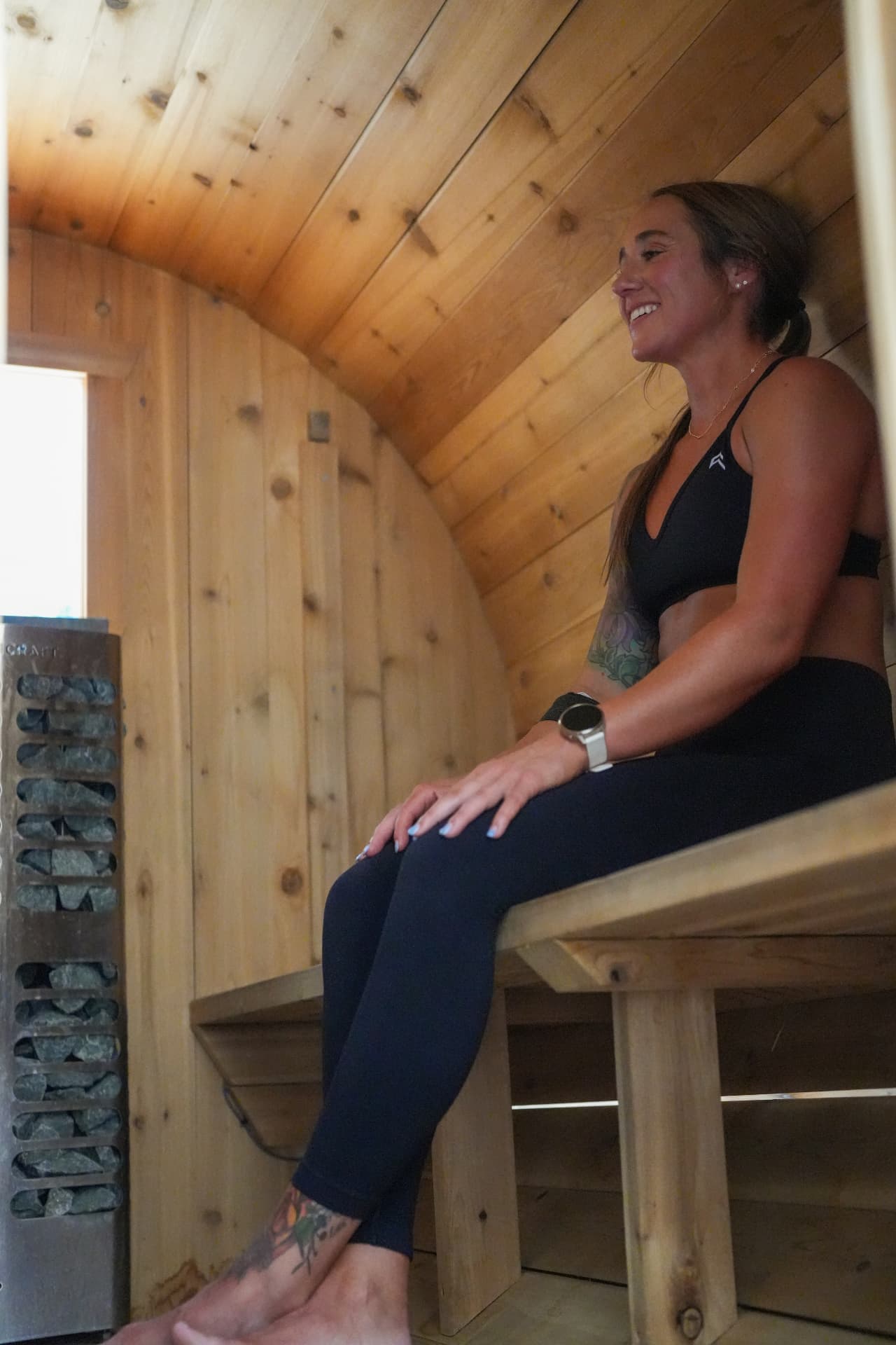 Member smiling inside the SISU barrel sauna at Arsenal Health